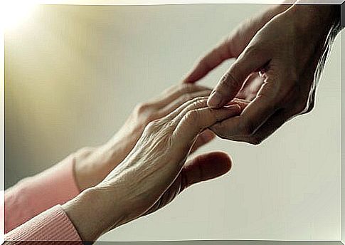 Hands of an adult holding those of an older person to help her