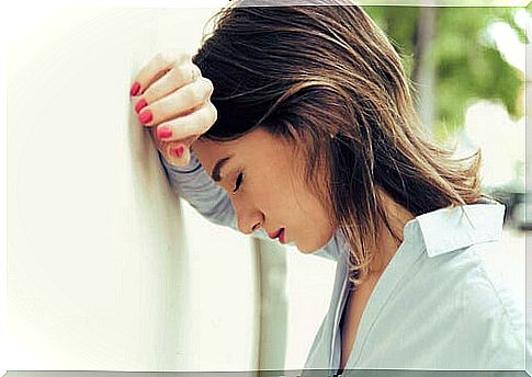 Stressed woman leaning head on wall