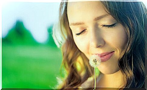 Woman thinking while smelling a dandelion