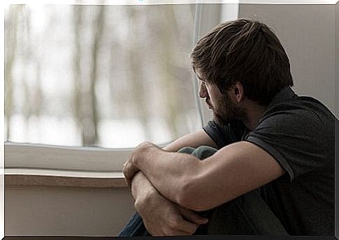 Worried boy looking out the window suffering for not being you